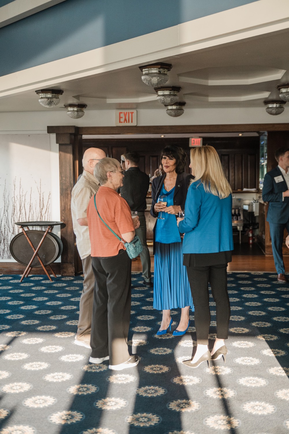 President Mantella talks to older couple and women while holding glasses